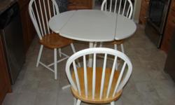 White 36" round table, Formica top, pedestal, two drop down leaves. Three matching chairs. See picture.
