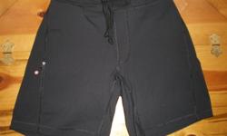 A pair of black Lululemon Men's Luon Shorts, size small. They are fully lined and have a faux fly, a zippered pocket on the right hip, with a red and white zipper pull. A drawstring is looped through 4 loops in the front, which gives the shorts a steady