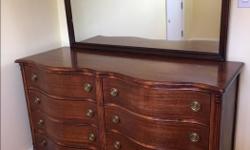 This is a solid mahogany serpentine front double dresser with mirror in regency style made about 1960 by the Peppler Furniture Company. It has eight drawers of similar size some with internal wood adjustable dividers. The mirror can be removed for