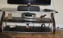 We have a 3 tier TV stand for sale, in dark wood trim, with sort of a pewter finish on front of shelves, with 3 black glass shelves, in perfect condition. The TV stand has a 46" Television on it. The stand measurements are 22" high, 54" Long, and 19"