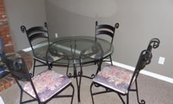 Beautifully crafted wrought iron table and 4 chairs. Table is 42" in diameter with tempered glass. Table and chairs are 1/2" wrought iron. Padded seat cushions have no rips or tears. Table and chair legs have scratch resistant pads on them. This table and